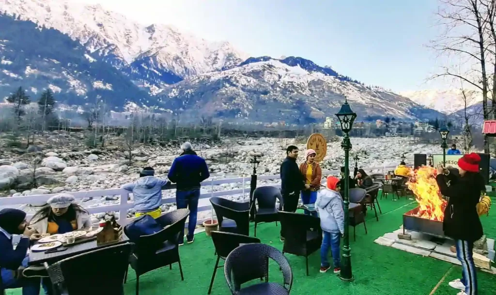 A cozy café in Manali with wooden décor and a mountain view.

