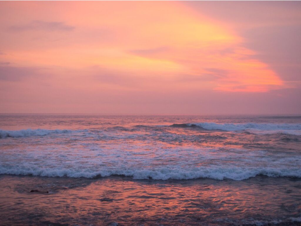 Serene view of Dwarka Beach at sunset, with golden sand and gentle waves along the Arabian Sea