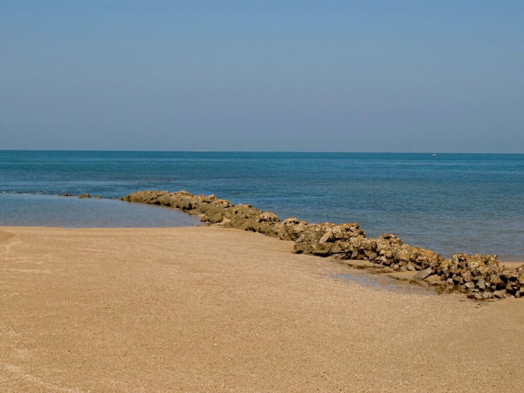 A scenic island near Dwarka with a ferry sailing towards it, one of the best places in dwarka