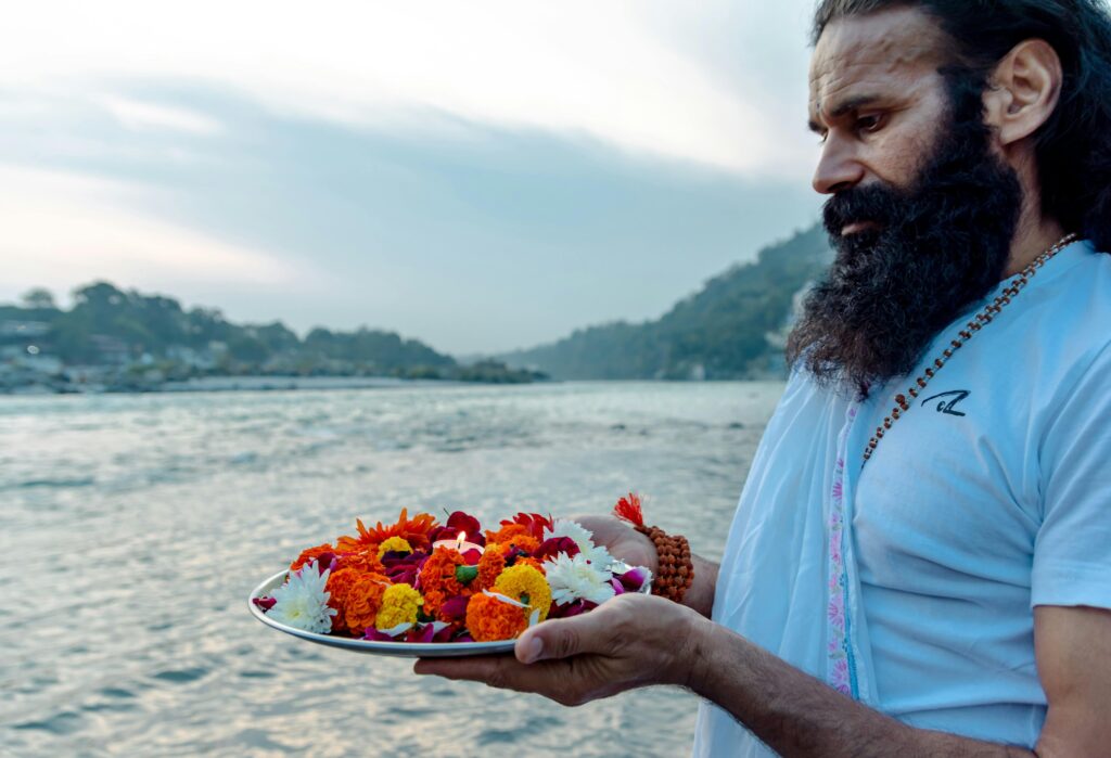 a devotee with flowers in a plate standing on the bank of river to play hindu rituals 